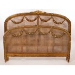 A French late 19th Century caned bed head and foot, each with reeded frame hung with swags,