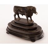 A bronze figure of a bull on a stepped oval plinth,