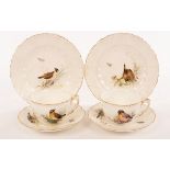 A pair of tea cups and saucers painted birds in foliage with gilt scrolling borders, Rd No 190547,
