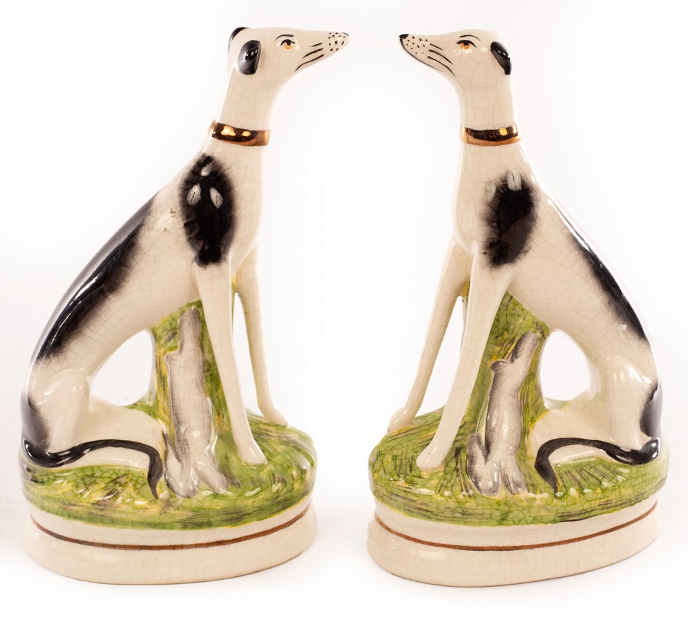 A pair of Staffordshire greyhounds each with a gilt collar and hare, on an oval base, 23.