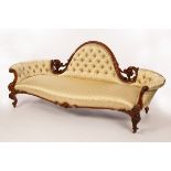 A Victorian sofa with central moulded arch, upholstered back and concave ends,