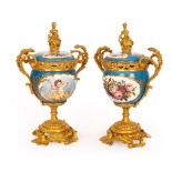 A pair of Sèvres style cups and covers, the blue ground with vignettes of putto and flowers,