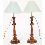 A pair of turned fruitwood candlesticks with metal drip trays, converted to lamps,