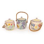 Poole Pottery, three floral biscuit barrels with raffia handles, all with printed marks,