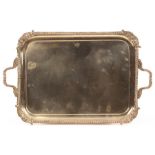 A silver plated tray of rectangular shape with shell and leaf scroll corners and gadrooned handles,