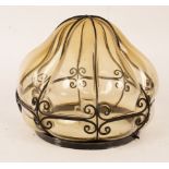 An amber tinted glass pendant ceiling light with wrought iron scroll decoration,