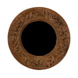 An Arts & Crafts oak circular mirror, the border carved foliage and thistles,