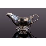 Guild of Handicraft, an Arts & Crafts hammered silver sauceboat, London 2003, on oval pedestal foot,