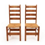 Heal & Son, a pair of Arts & Crafts oak and rush seat ladderback chairs,