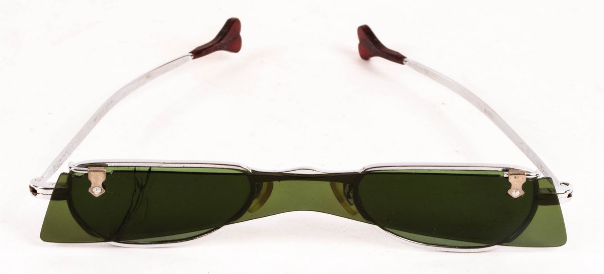 A pair of retro vintage sunglasses, 1960s, with flip-up green lenses (one cracked),