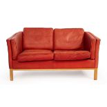 A Danish Stouby red leather two-seater sofa, with label,
