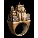 A silver gilt and enamel architectural ring, modelled as a city,