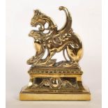 A brass door stop of griffin form, weighted,