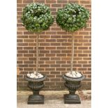 A pair of decorative urns containing faux bay trees,