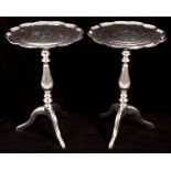 A pair of metal tripod tables with lobed tops,