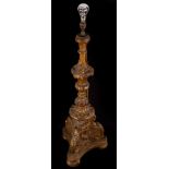 An Italian carved giltwood alter type candlestick on a tri-form base and bun feet, 86cm high,