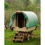 A child's gypsy bow-top caravan with a canvas roof, the painted wooden frame with steering axle,