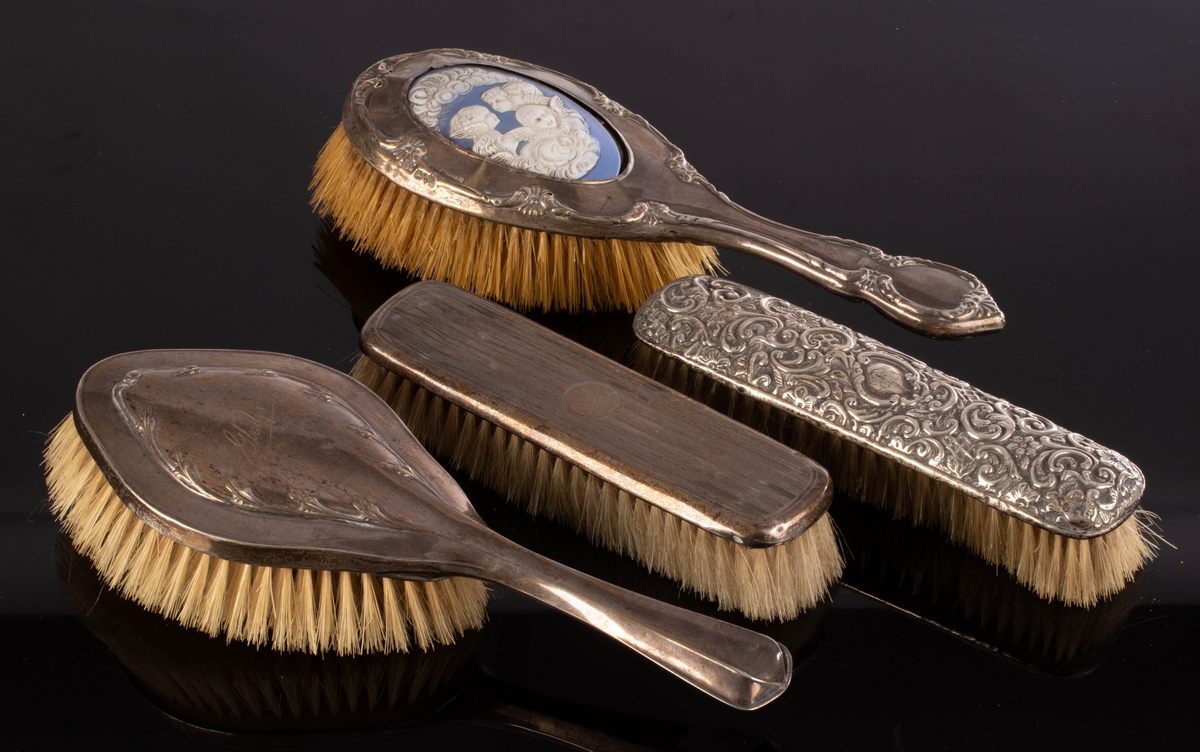 A silver mounted dressing brush with a porcelain back and three other silver mounted brushes