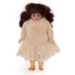 A German small bisque head doll with sleepy eyes and a composition body, in a crocheted dress,