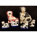 Four Staffordshire figures of seated spaniels and a pair of cats recumbent on cushions,