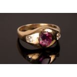 A ruby and diamond three-stone ring in an unmarked yellow metal gypsy setting, size L,