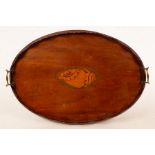 An Edwardian oval mahogany tray with wavy rim and central inlaid shell, brass carrying handles,