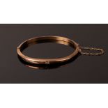 A 9ct rose gold hinged bangle, gypsy set with a small diamond, internal measurement 5.