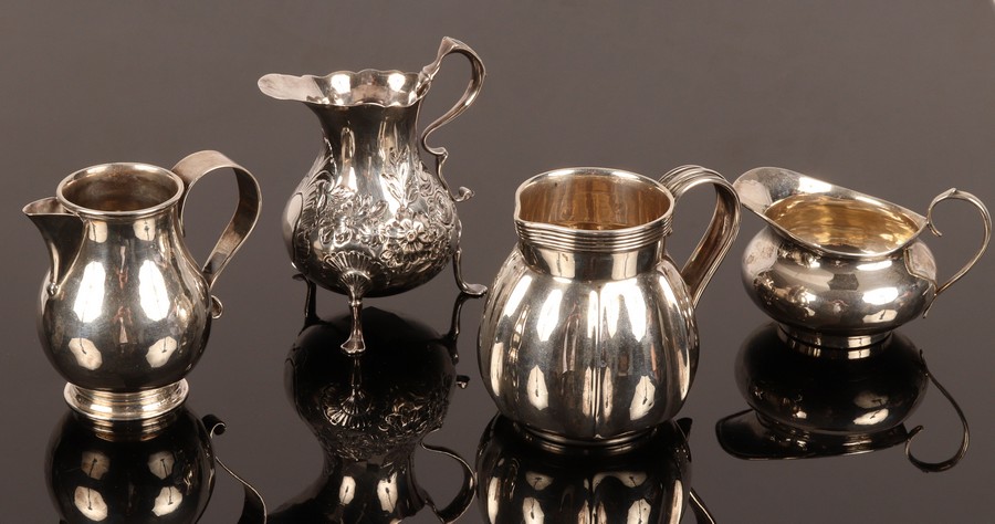 Four silver jugs, including one of baluster shape, London 1912 and another of squat circular form,