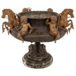 A metal jardinière with applied cherubs and water horses on a circular veined marble plinth,
