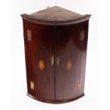 A 19th Century mahogany bowfront hanging corner cupboard, the twin doors with central shell paterae,