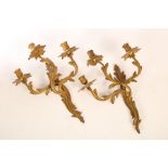 A pair of gilt metal three-branch wall lights of scrolling form,