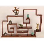 A Chinese wall shelf containing a small collection of carved hardstone and cloisonné ornaments,