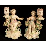A matched pair of Derby porcelain cherub candlesticks, in pink and turquoise,