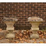 A pair of weathered stone square garden vases of fluted tapering form on pedestal bases,