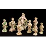 Eight small porcelain models of putti encrusted with flowers and carrying baskets, several Derby,