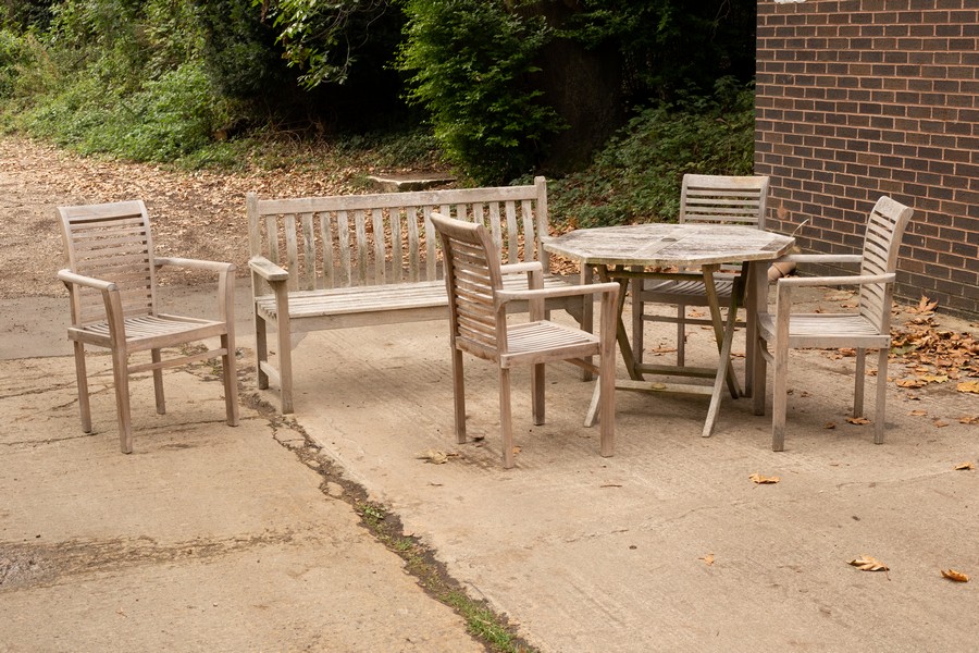 A teak slatted folding garden table, 100cm wide, four matching armchairs and a slatted garden seat,