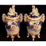 A pair of Japanese pottery vases, the covers with temple dog finials, the vases each on four legs,