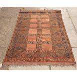 An Afghan village rug of geometric design, deep rusty brown and red with some blues,