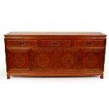 A Chinese hardwood sideboard, fitted three drawers above cupboard doors carved with dragon motifs,