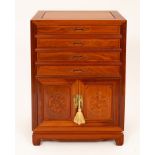 A Chinese hardwood side cabinet, fitted four drawers above cupboard doors carved with dragon motifs,