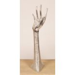 A contemporary composite sculpture of a raised arm with textured silver coloured overlay,