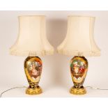 A pair of porcelain table lamps decorated panels of interior scenes with gilt borders to a cobalt