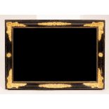 An ebonised wall mirror with gilded floral spandrels,