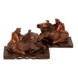 A pair of 20th Century Japanese carved wooden bulls with boys riding behind on wooden plinths,