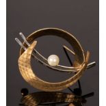A bi-colour 9ct gold brooch of stylised circular shape centred by a pearl,