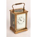 A gilt cased eight-day carriage clock with white enamel dial, striking on a gong,
