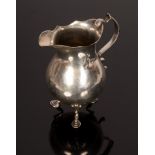 A Georgian silver jug, marks rubbed, the pear-shaped jug with wavy rim on three stepped feet,