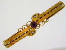 An Edwardian 15ct gold bangle set with approx. 0.65ct ruby & two small diamonds. 54mm internal diame