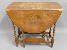 A 1920's oak drop leaf table with barley twist sup