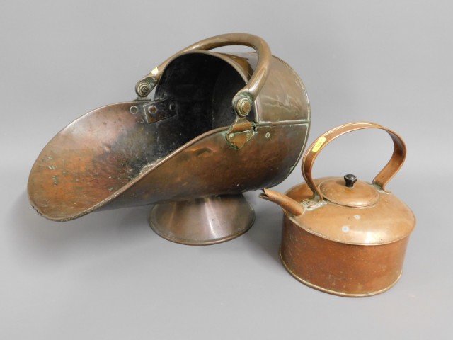 A copper coal scuttle twinned with a copper kettle